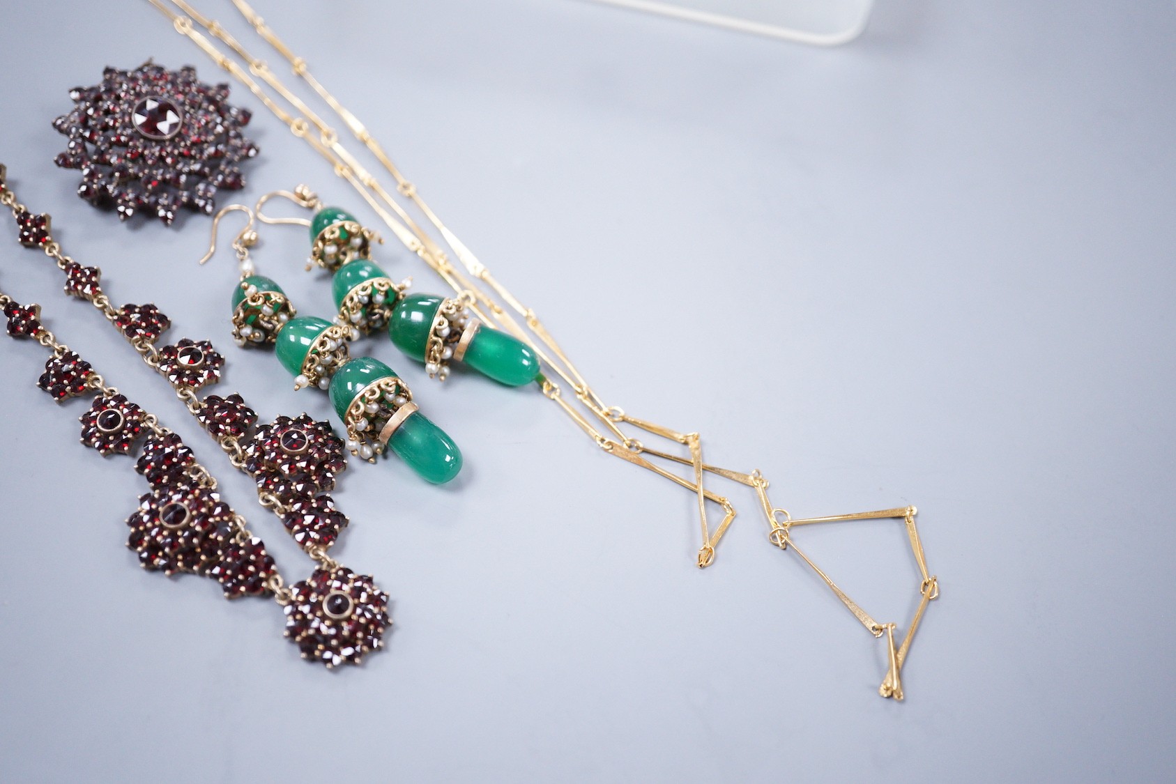 A Victorian gilt white metal and facetted garnet cluster set necklace, 42cm, a similar brooch, a pair of chrysoprase set drop earrings and a gilt metal necklace.